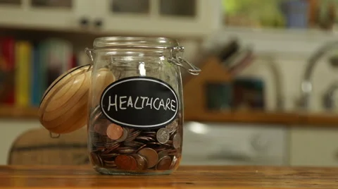 Loose change put in a saving jar, reading Healthcare Stock Footage 44116868