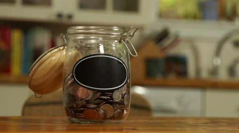 Loose change put in a saving jar, with blank label Stock Footage 44116873