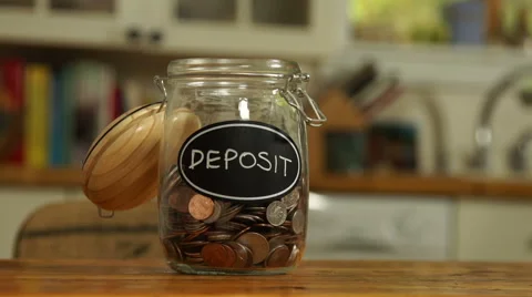 Loose change put in a saving jar, reading Deposit Stock Footage 44116923