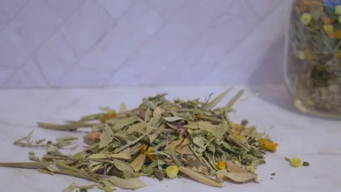 Loose ginger tea leaves and herbs on white marble table with glass jar of tea Stock Footage 328577794