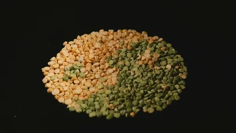 Loose green and yellow split peas rotate on black background Stock Footage 78629489