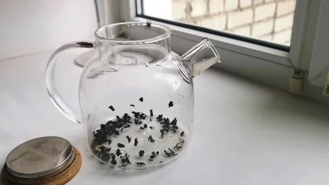 Loose leaf tea brewing in glass teapot close up, hot beverage preparation, cozy Stock Footage 333271887