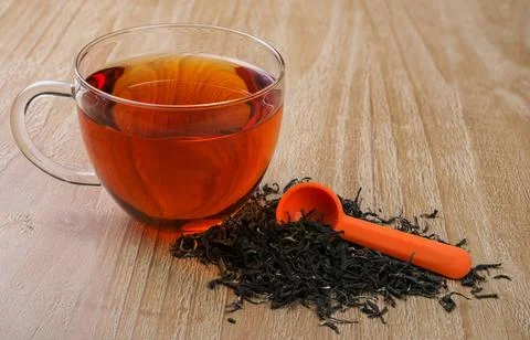 Loose leaf tea cup of tea and pile of loose leaf tea on vintage wooden tab... Fotos Stock
