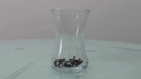 Loose tea leaves falling into a clear glass teacup. Turkish tea Video stock 284043133