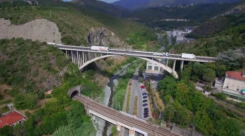 Lorry trucks move on road bridge in rock mountain up railway bridge 4k aerial Stock Footage 67547937