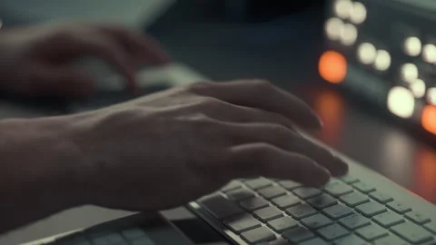 Lose-up of hands typing on a modern keyboard in a dimly lit workspace Stock Footage 299542369