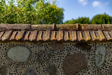 Lose-up of a rustic stone wall with a distinctive tiled roof. The wall itse.. Stock Photos