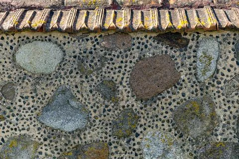 Lose-up of a rustic stone wall with a distinctive tiled roof. The wall itse.. Stock Photos