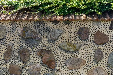 Lose-up of a rustic stone wall with a distinctive tiled roof. The wall itse.. Stock Photos