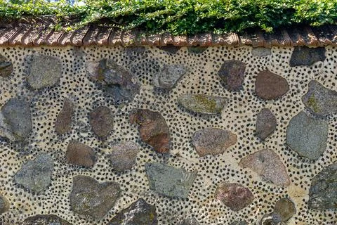 Lose-up of a rustic stone wall with a distinctive tiled roof. The wall itse.. Stock Photos