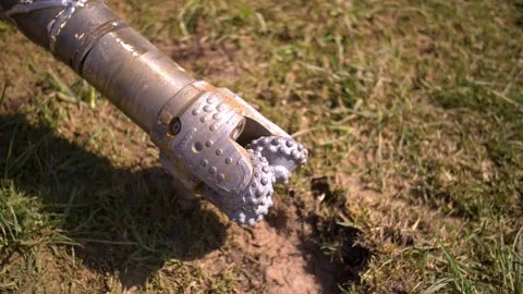 Lose-up of a silver drill bit with rotating teeth, partially embedded in the Video stock 303132985