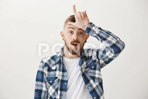 Loser is destiny. Handsome young european brother in blue plain shirt showing Stock Photos