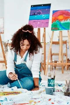Lost in an artistic world. an attractive young artist sitting alone and painting Stock Photos