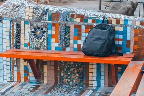 A lost backpack lying on a park bench. Stock Photos