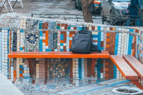 A lost backpack lying on a park bench. Stock Photos