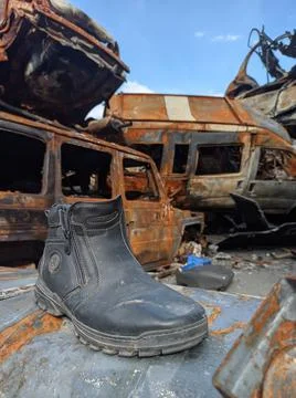 Lost boot in front of shot and burned cars during russian invasion of Ukraine Stock Photos
