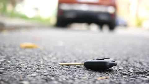 Lost car key on the asphalt street with a blurry car in the background, a c.. Stock Footage 333031663