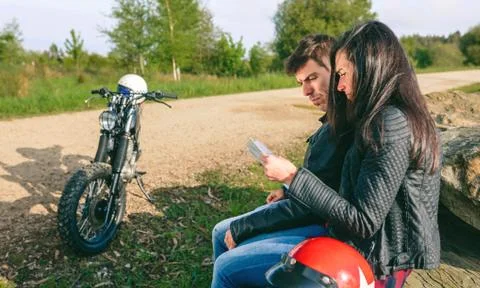 Lost couple sitting looking at a map with motorcycle Stock Photos