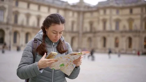 Lost female tourist using two maps two find a way in new city, woman googling Stock Footage 98896128