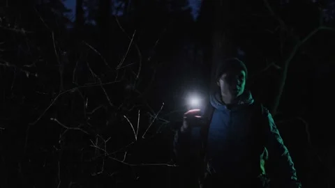 A lost man with a backpack pushes through bushes in a dark forest at night Stock Footage 302568972