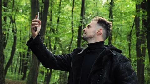 Lost man in forest holding a mobile phone not receiving any cellphone signal. Video stock 221322984