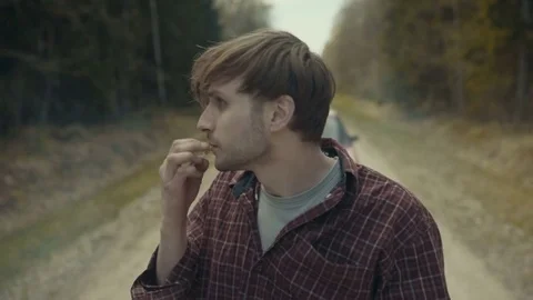 Lost man gets out of car in the middle of the forest road and lights cigarette Stock Footage 82740212
