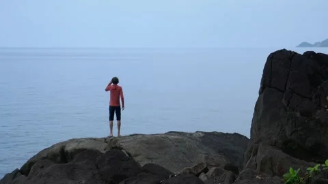 A lost man on the seashore, asks for help, looks through binocular Stock Footage 293189570