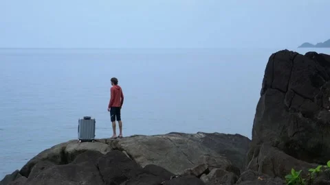 A lost man on the seashore with a suitcase, asking for help Stock Footage 293189817