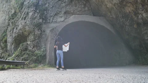 A lost tourist looks at a map in front of the entrance of a tunnel Video stock 143643136