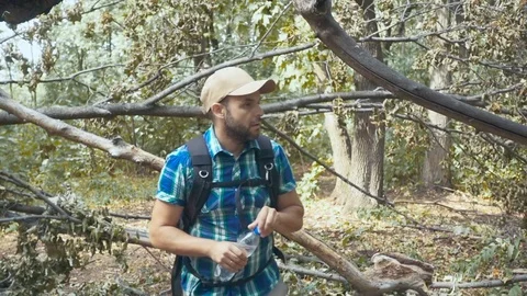 Lost tourist man close-up walking through the forest drinks water. man with b Stock Footage