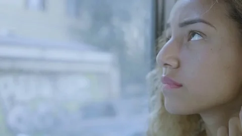 Lost woman sitting sad and pensive near the window of a bus in the city Stock Footage