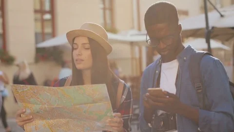 Lost young cute couple looking at the city map standing in centre of town. Young Video stock 81832078