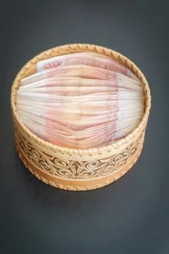 A lot of banknotes worth five thousand rubles are in a round wooden wicker bo Stock Photos