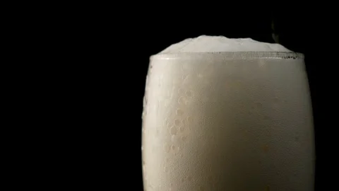 A lot of beer foam is running down the glass. Close up. Slow motion. Black Stock Footage 135123223