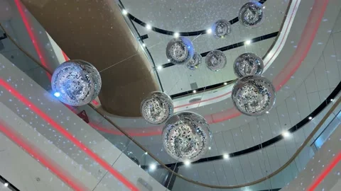 A lot of bright silver disco balls throw glare under the ceiling in the mall Stock Footage 130953754