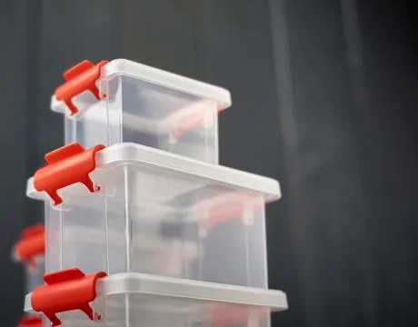 A lot of clear plastic object storage boxes with orange accents stacked on fl Stock Photos
