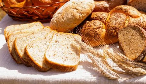 Lot of different flavored bread, wheat, rye, on the table in the field outside Stock Photos