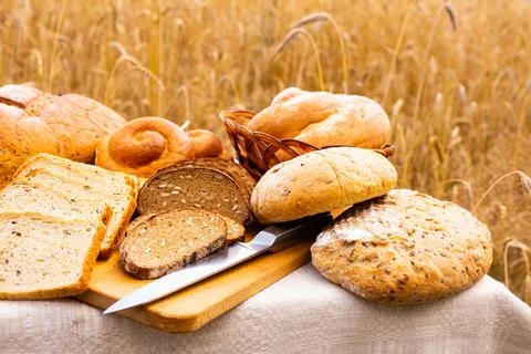 Lot of different flavored bread, wheat, rye, on the table in the field outside Stock Photos