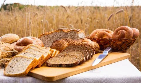 Lot of different flavored bread, wheat, rye, on the table in the field outside Stock Photos