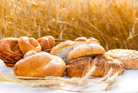 Lot of different flavored bread, wheat, rye, on the table in the field outside Stock Photos