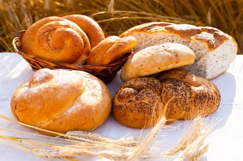 Lot of different flavored bread, wheat, rye, on the table in the field outside Stock Photos