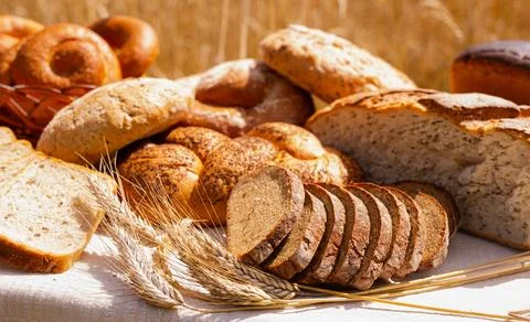 Lot of different flavored bread, wheat, rye, on the table in the field outside Stock Photos