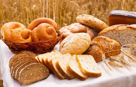 Lot of different flavored bread, wheat, rye, on the table in the field outside Stock Photos