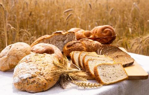 Lot of different flavored bread, wheat, rye, on the table in the field outside Stock Photos