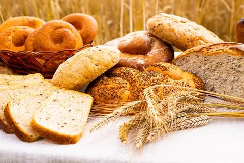 Lot of different flavored bread, wheat, rye, on the table in the field outside Stock Photos