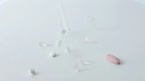 A lot of different pills are falling on a white background in slow motion Stock Footage 194585107