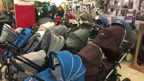 Lot of different strollers are in kids store. Pregnant woman chooses one 動画素材 104565374