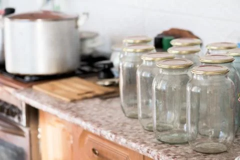 A lot of glass jars standing on the table in front of preserving . near gas s Stock Photos