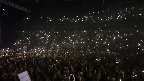 A lot of lights from cellphones in hands of crowd of people which waving Stock Footage