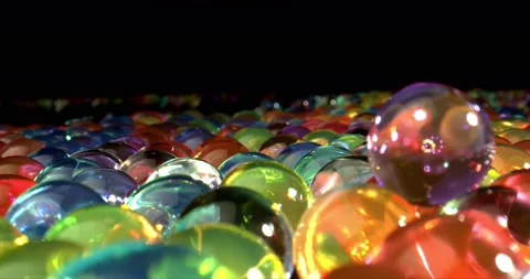 A lot of many colored hydrogel balls for plants lying on black surface at black Stock Footage 148520748